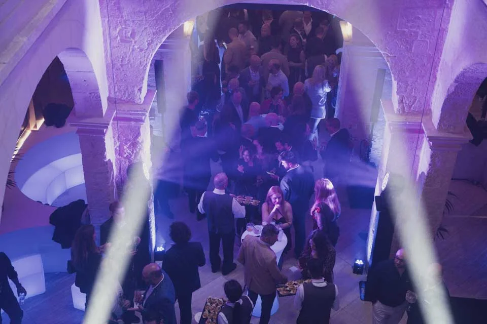 The gathering beneath illuminated arches · Civil Service Club, Valletta